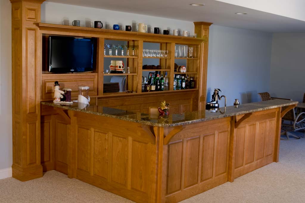 A solid cherry bar with a back bar of columns and paneling.