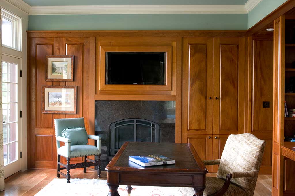 A mahogany study using bookmatched panels and housing an entertainment center and media storage.