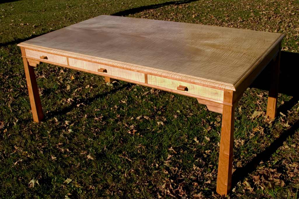 A map table / writing desk in curly maple and cherry. Desk is 48" x 72" two board, bookmatched top.
