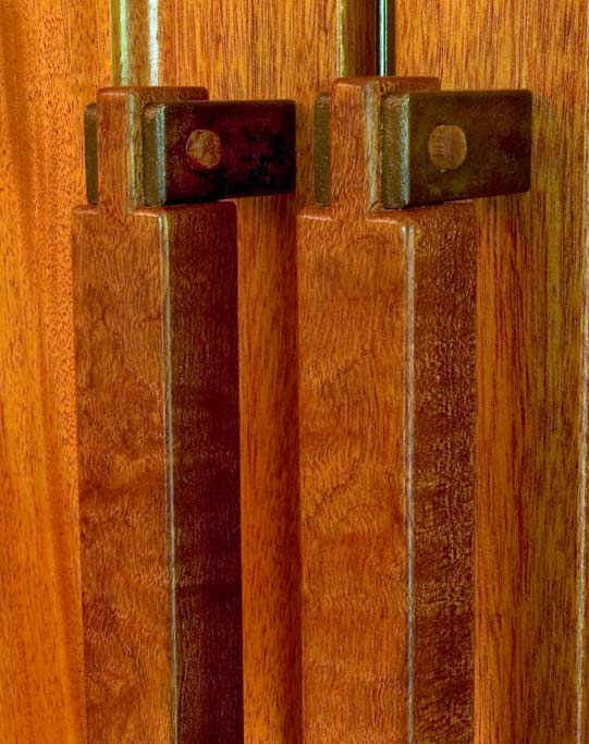 These refrigerator handles show our willingness to mix materials when appropriate. To make the conection to the wood paneled front of the fridge, we utilized solid brass which was hammered and a craftsman era patina applied. The mahogany handles were pegged in an open bridle joint.